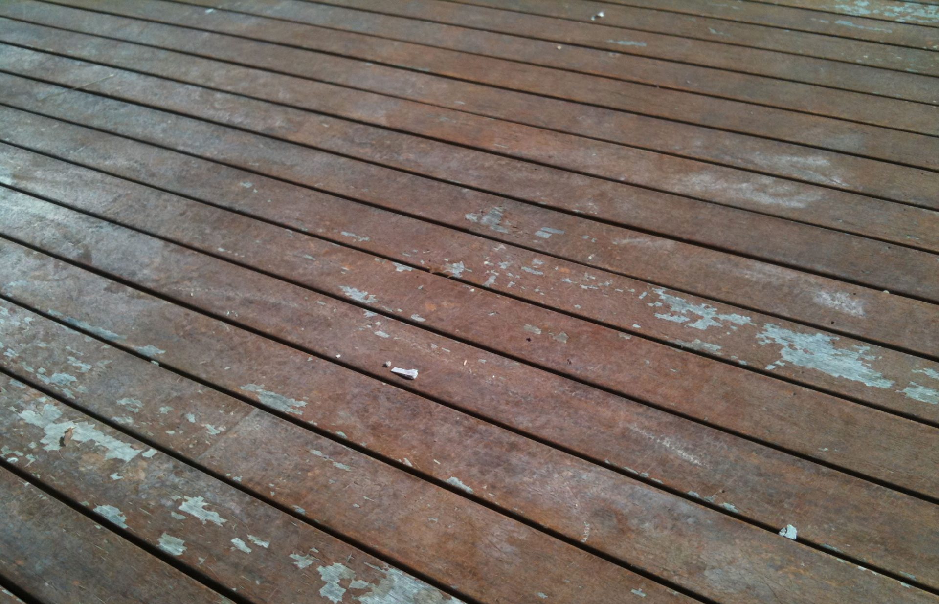 Stained dark timber deck with peeling marks